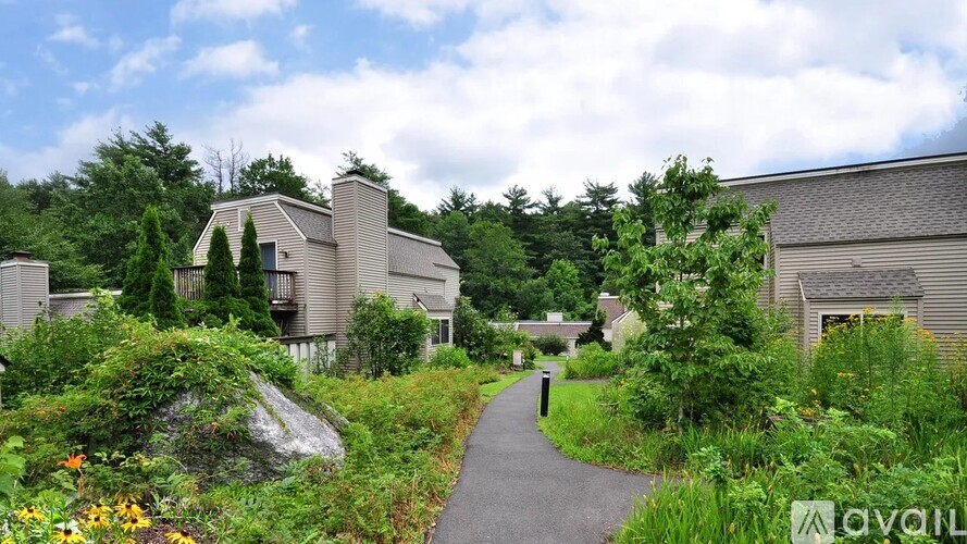 A pathway leads through a lush green garden to a building.