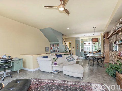 A living room with a white couch, a black leather chair, and a rug on the floor.