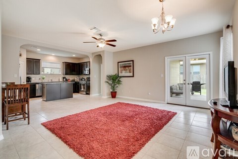 A living room with a red rug in the middle.