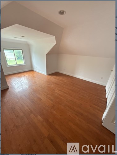 A room with wooden flooring and a window.