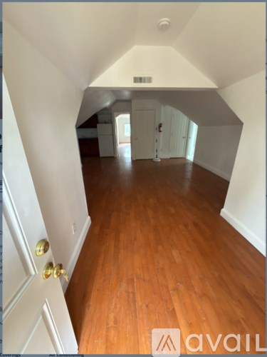 A hallway with a wooden floor and white walls.