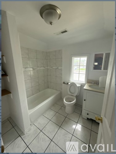 A white bathroom with a toilet, sink, and bathtub.