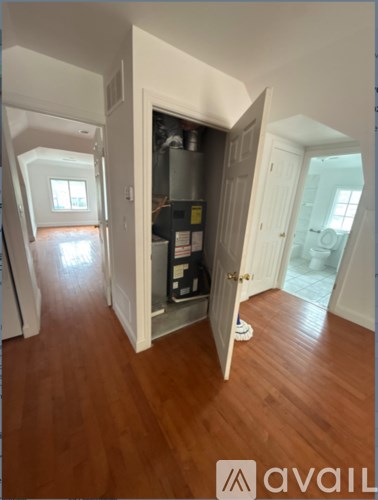 A room with a wooden floor and a doorway leading to a storage area.