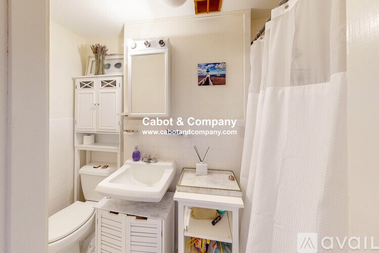 A white bathroom with a sink, toilet, and a cabinet.