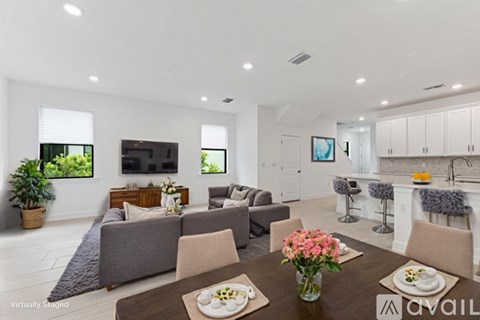 A modern living room with a dining table set for two and a kitchen area in the background.