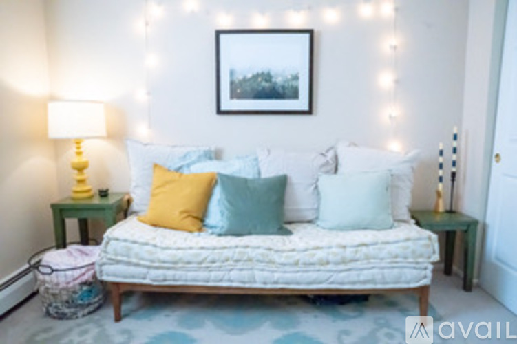 A bedroom with a bed, two lamps, and a picture on the wall.