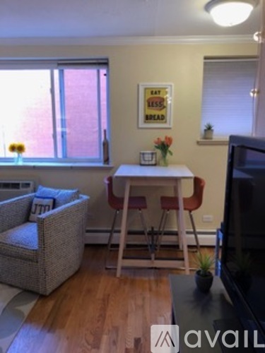 A living room with a couch, chair, and a small table with a vase of flowers on it.