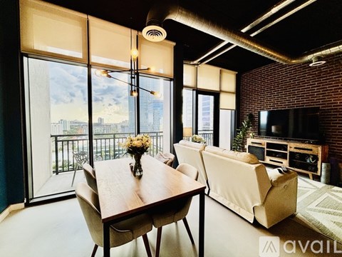 A modern living room with a wooden table and chairs, a sofa, and a television.