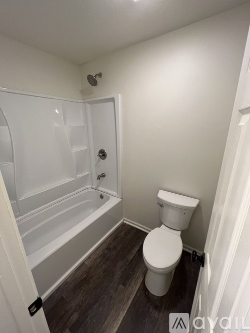 A white toilet sits next to a bathtub in a small bathroom.