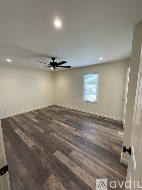 A room with a ceiling fan and a window with blinds.