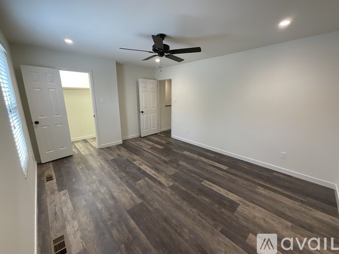 A room with a ceiling fan and wooden flooring.