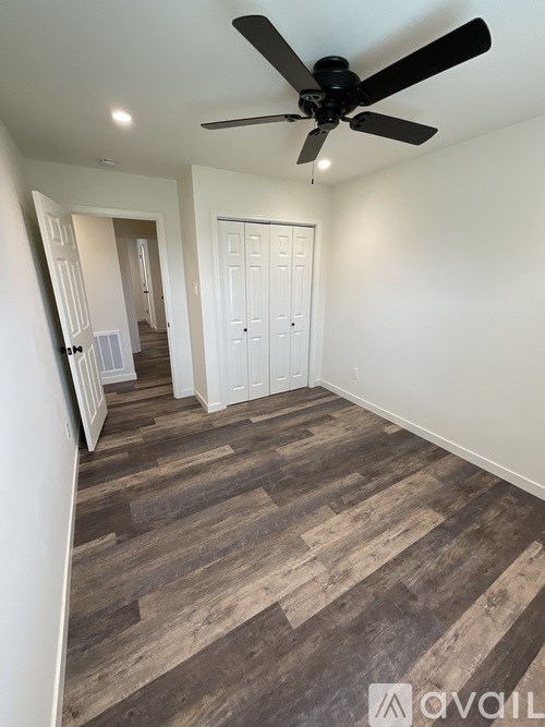 A room with a ceiling fan and wooden flooring.
