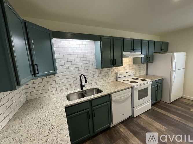 A kitchen with dark green cabinets and white appliances.