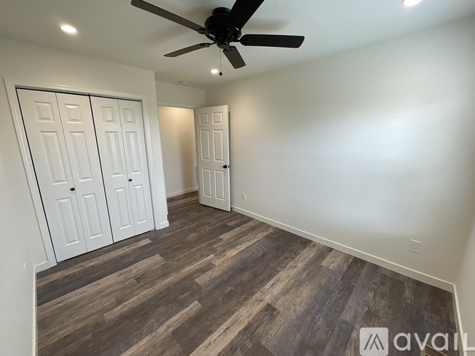 A room with a ceiling fan and wood flooring.
