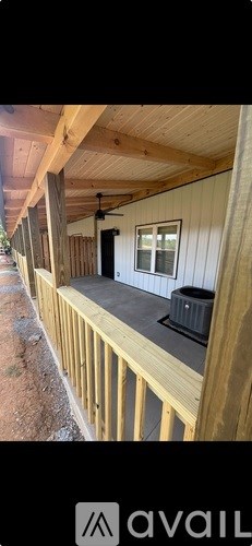 A wooden deck with a black trash can and a white wall.