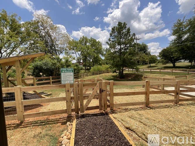 A wooden gate with a sign in front of a field.