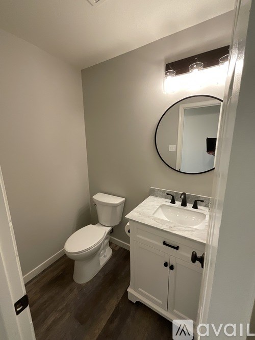 A bathroom with a toilet, sink and mirror.
