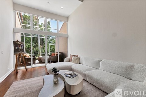 A living room with a white couch and a coffee table in front of a large window.