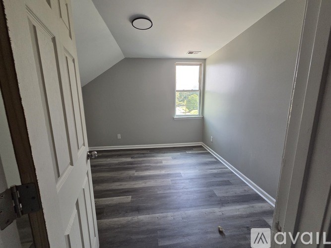 A room with a window and wooden flooring.