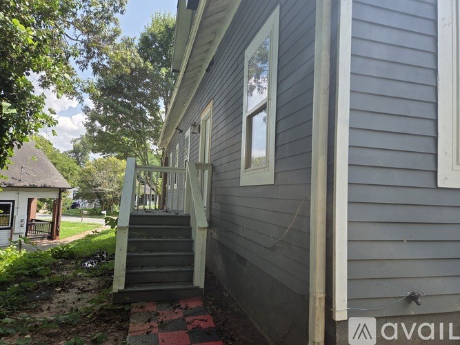 A house with a grey siding and a white trim is shown with a staircase leading to the front door.