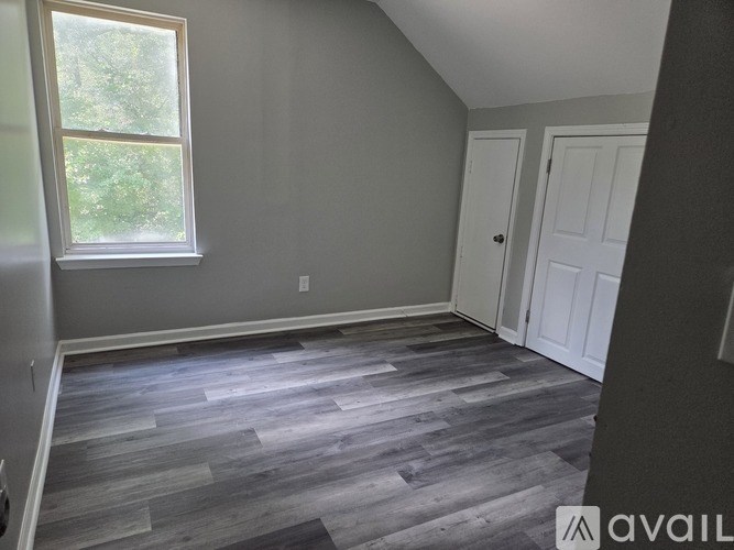 A room with a window and wooden flooring.