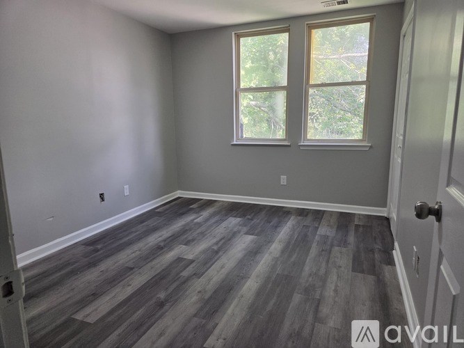 A room with a grey floor and a window showing trees outside.