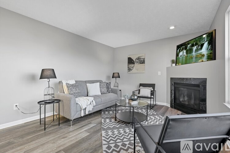 A living room with a grey couch, a black chair, and a fireplace.