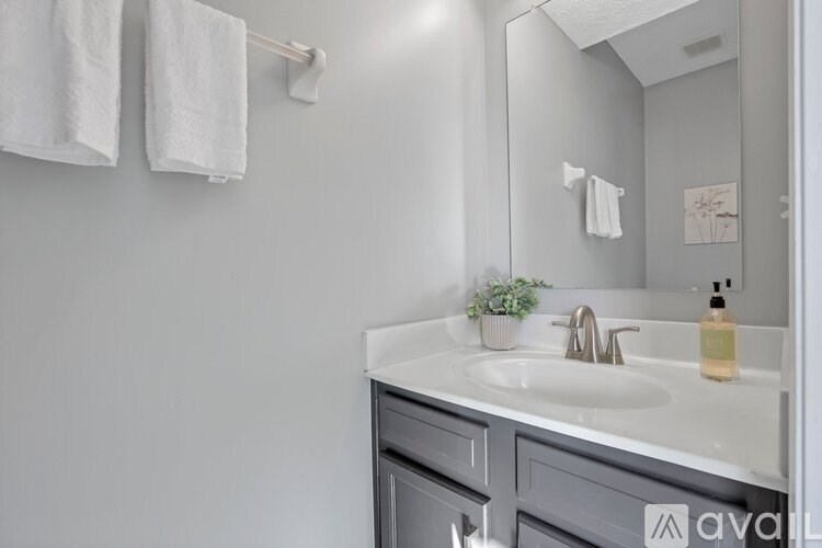 A bathroom with a white sink and grey cabinets.