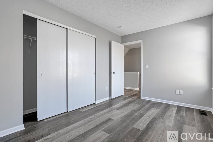 A room with a grey floor and white walls has a white door and a white cabinet.