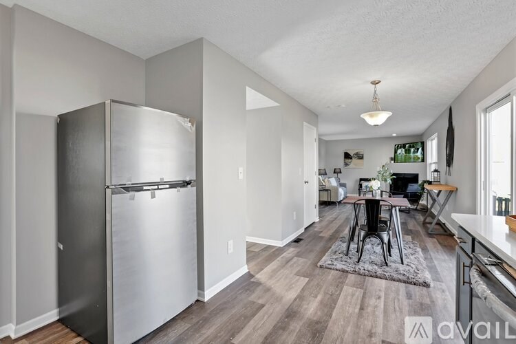 A kitchen with a refrigerator and a dining table.