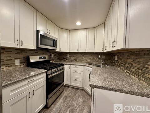 A kitchen with white cabinets and a granite countertop.