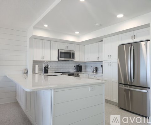 A modern kitchen with white cabinets and a stainless steel refrigerator.