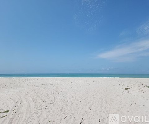 A beach with white sand and a clear blue sky.