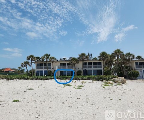 A blue circle is on a sandy beach in front of a building.