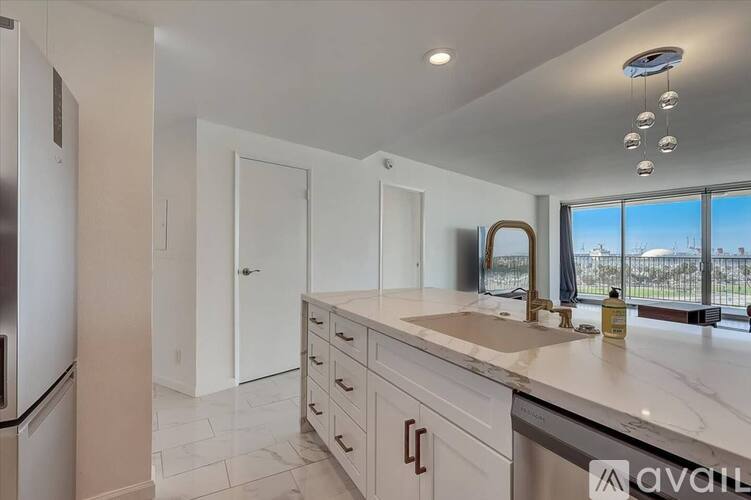 A modern kitchen with white cabinets and a marble countertop.