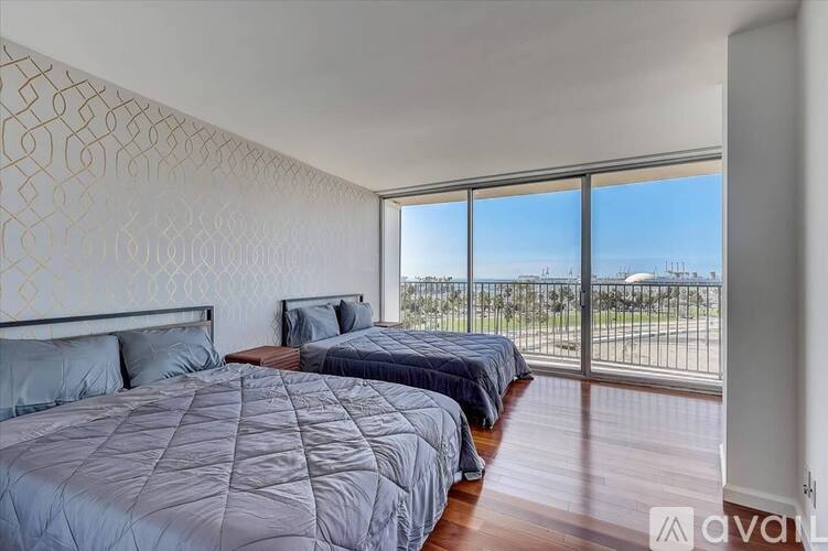 A bedroom with two beds and a large window overlooking a field.