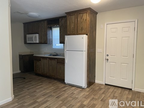 A kitchen with a white refrigerator and wooden cabinets.