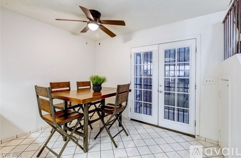 A dining room with a table and chairs and a ceiling fan.