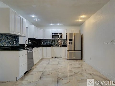 A kitchen with white cabinets and a marble floor.
