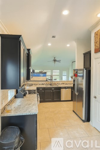 A kitchen with black cabinets and a marble countertop.