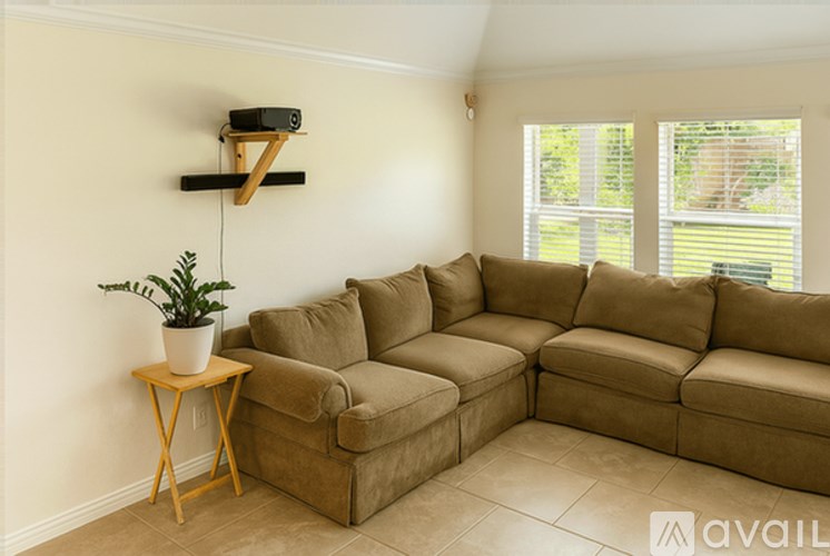 A living room with a brown couch and a small table with a plant on it.
