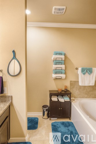 A bathroom with a tub, towel rack, and a towel hanging on the wall.