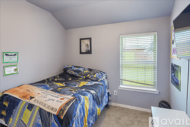 A bedroom with a bed covered in a blue and yellow comforter.
