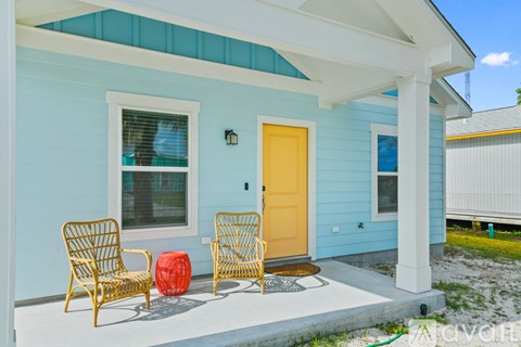 A yellow chair sits on a porch with a blue house in the background.