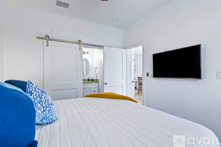 A bedroom with a bed, a chair, a mirror, and a television.