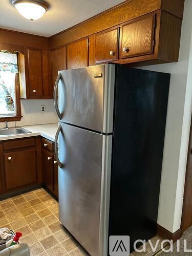 A stainless steel refrigerator in a kitchen with wooden cabinets.