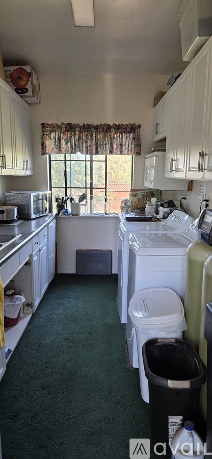 A kitchen with white cabinets and a window with a curtain.