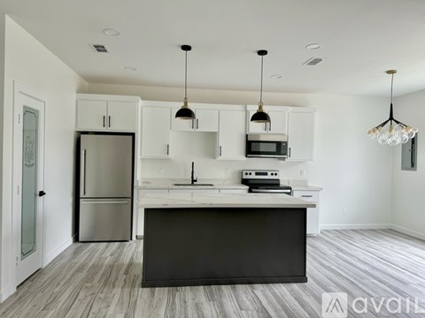 A modern kitchen with a large island and pendant lights.