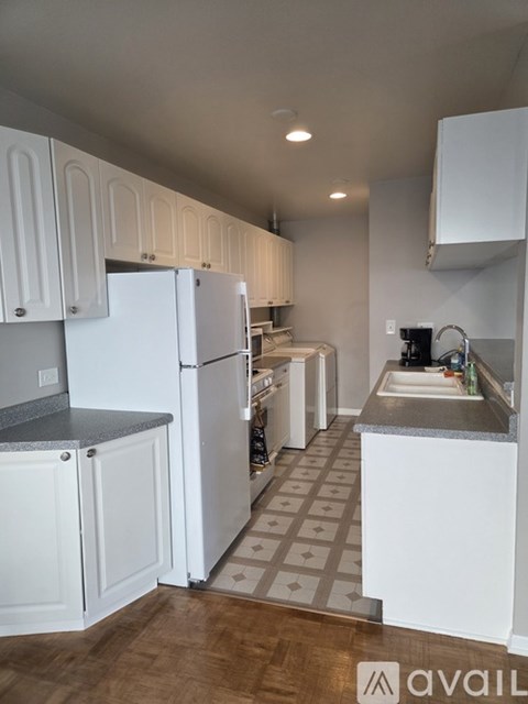 A kitchen with white cabinets and a tiled floor.
