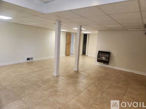 A spacious room with tiled flooring and a television in the corner.